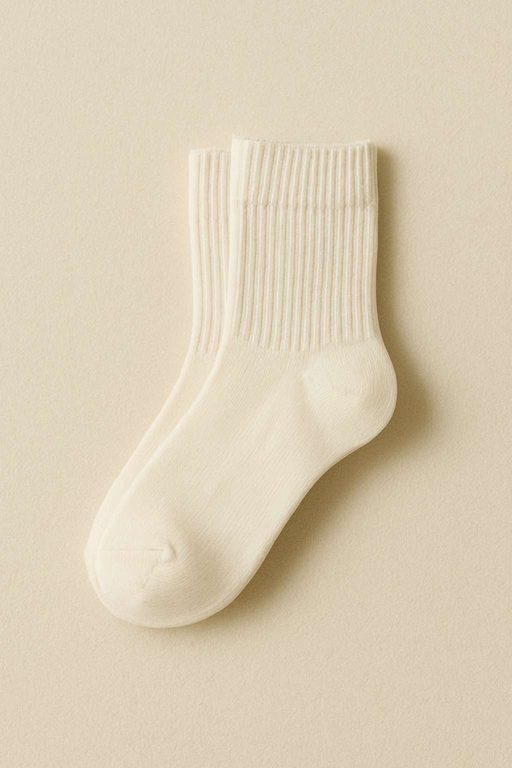 clean editorial flat lay of minimalist cotton socks folded neatly on a cream-toned backdrop.