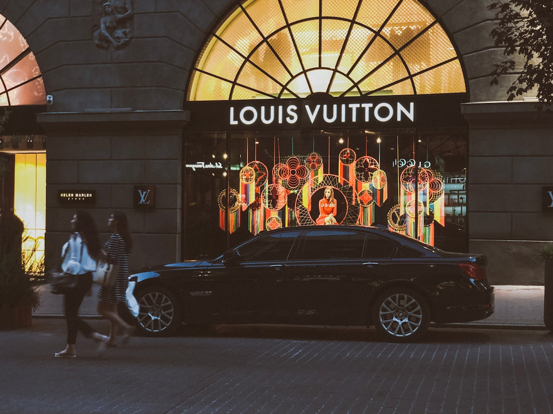 black sedan parking near Louis Vuitton building and two women walking near road