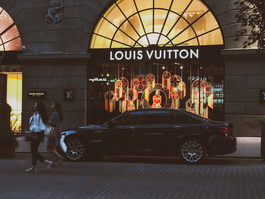 black sedan parking near Louis Vuitton building and two women walking near road