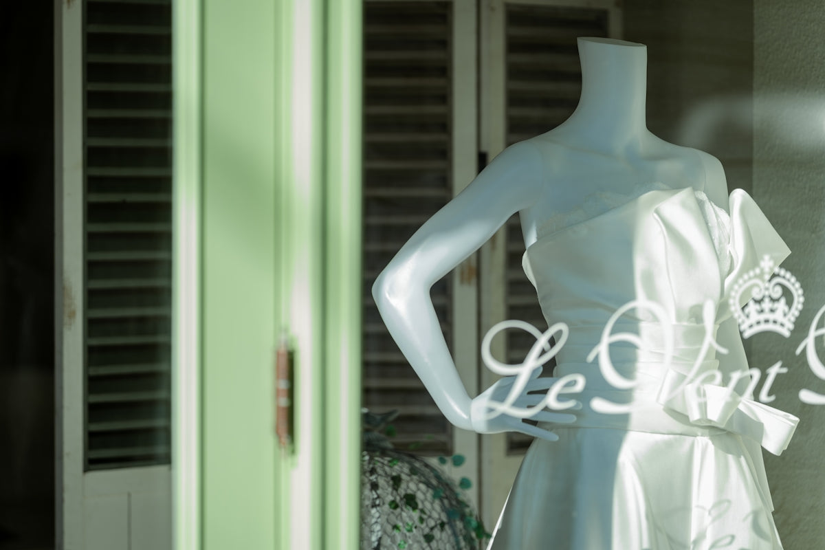 a mannequin dressed in a white dress in front of a window