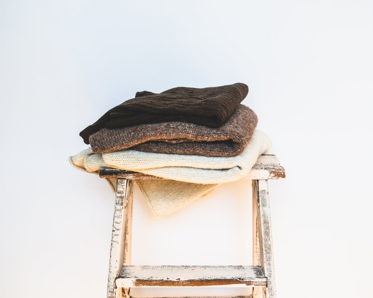 a stack of clothes sitting on top of a wooden stool