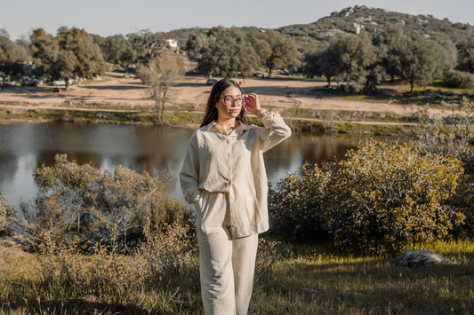 a woman standing in a field next to a lake