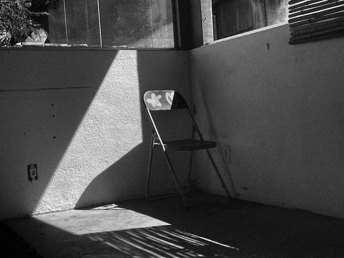 Shadows fall on a chair in an empty room.