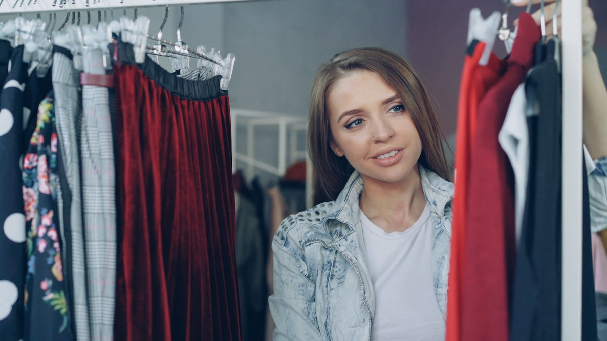 Woman browses clothing racks at a retail store.