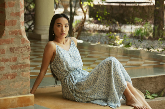 A woman in a floral dress sits outdoors.