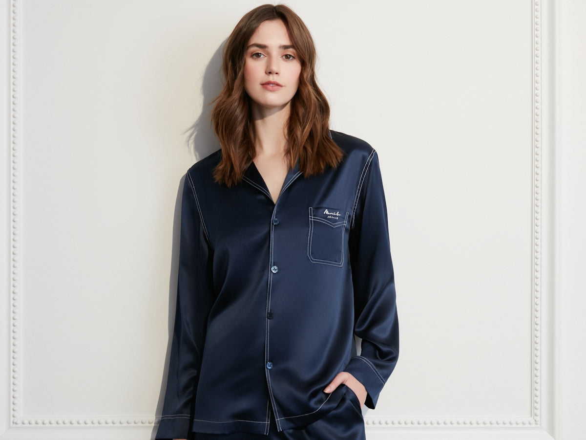 Woman wearing navy blue silk pajamas with white trim.