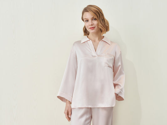 A woman in a light pink silk pajama set.