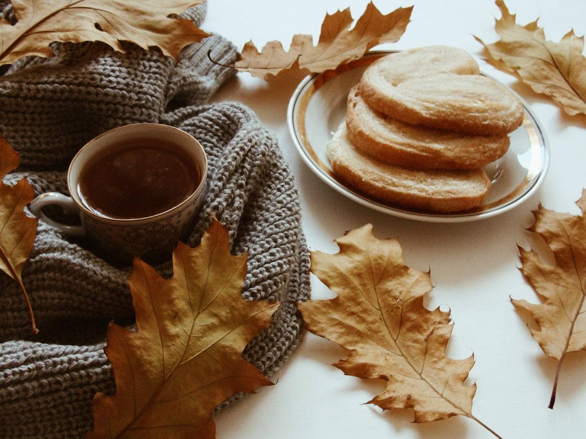 Cozy autumn scene with tea, cookies, and fallen leaves.
