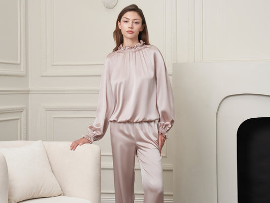 Woman in satin pajamas posing in a room.