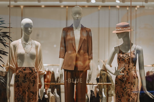 Three mannequins display fashionable clothing in a store window.