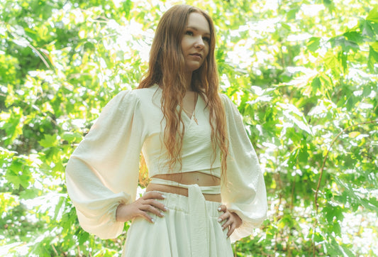 Red-haired woman in white standing with hands on hips outdoors