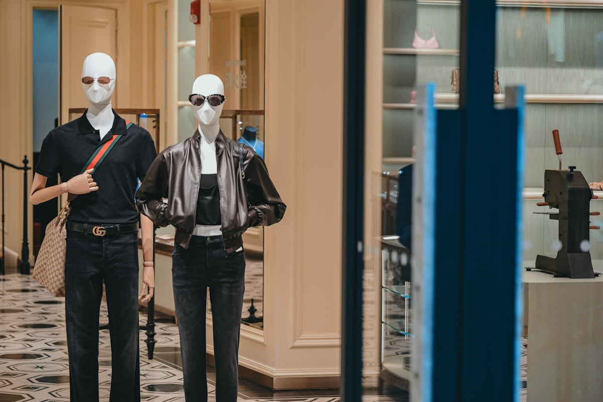 Two mannequins wearing black outfits and sunglasses in a store.