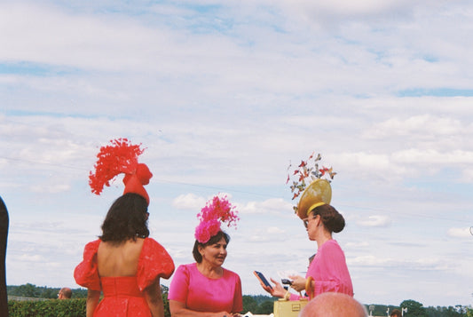 Women in vibrant dresses and elaborate hats outdoors
