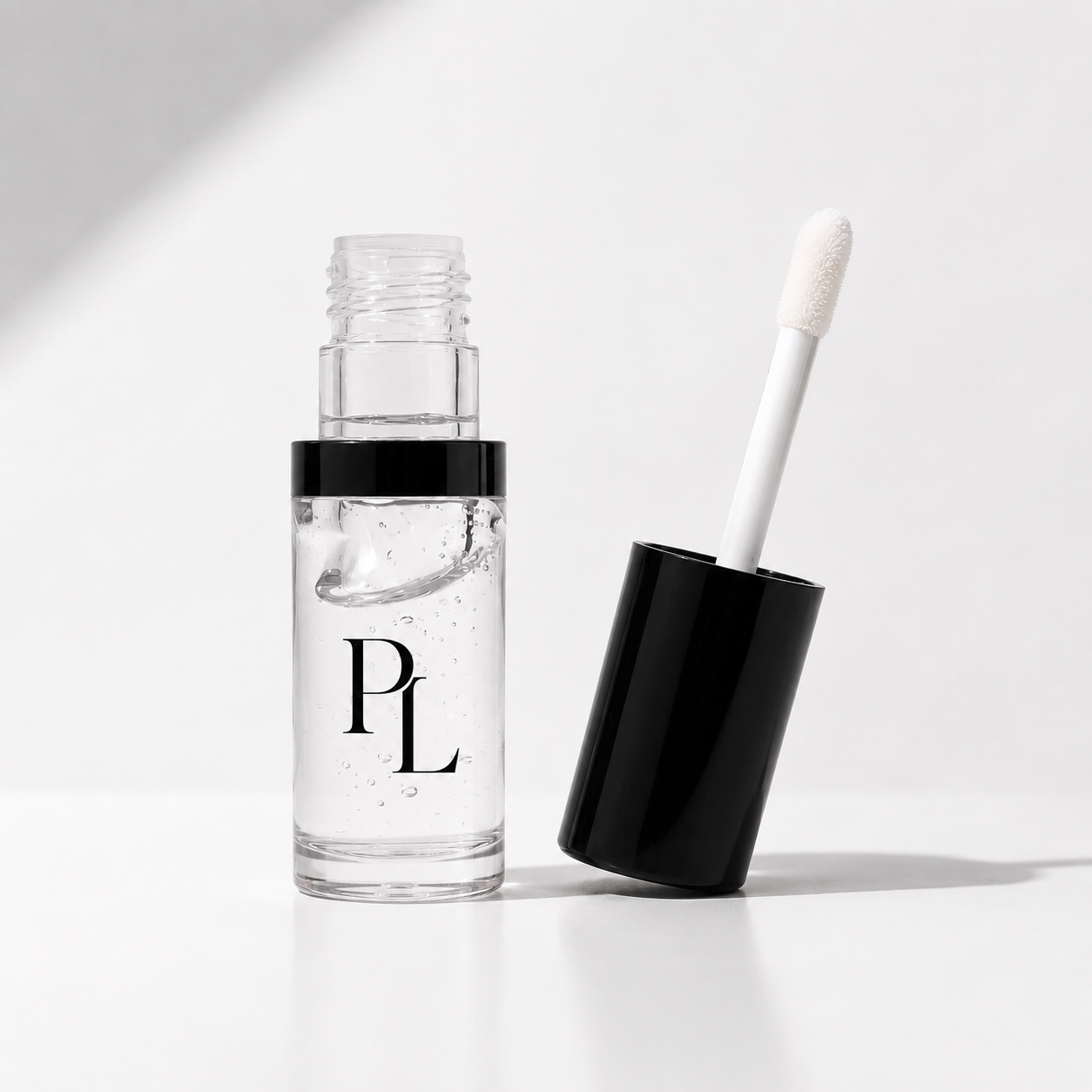 Clear cosmetic bottle with black cap and white applicator on a light gray background