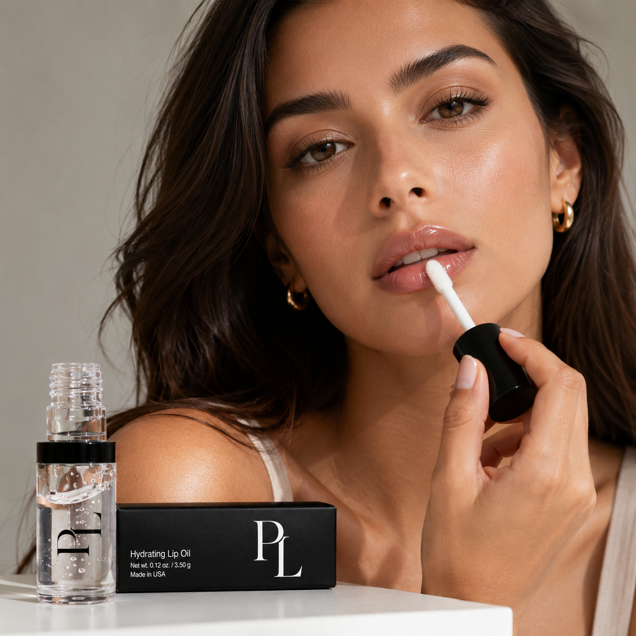 Woman applying lip oil with a product box and bottle in the foreground